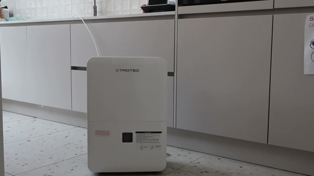 Luftentfeuchter Trotec TTK 127 E mit Ablassschlauch vor den Küchenschränken
